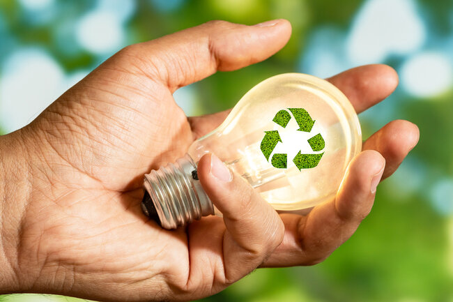 Glühbirne mit grünem Recycling-Zeichen in einer Hand 