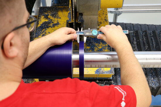 Mann misst Klebebandbreite mit Schublehre.