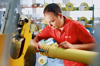 Mitarbeiter misst Klebebandbreite mit Schublehre.