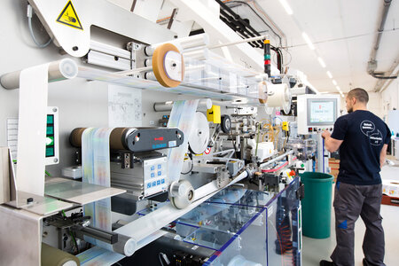 Mitarbeiter bedient Maschine zur Tubenherstellung.