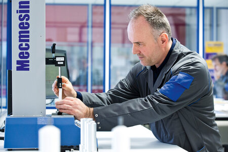 Mitarbeiter prüft mit einer Maschine die Qualität einer Tube.