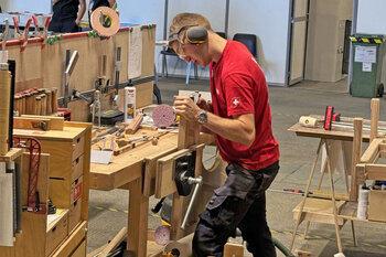 Loïc Santschi klemmt ein Bauteil zur Bearbeitung an der Werkbank ein.