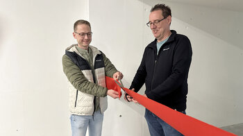 Zwei Mitarbeitende durchschneiden das symbolische rote Band.