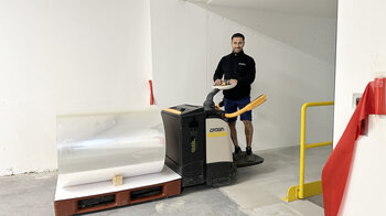 Deichselgerät mit einer Rolle Folie fährt durch den Logistiktunnel. 