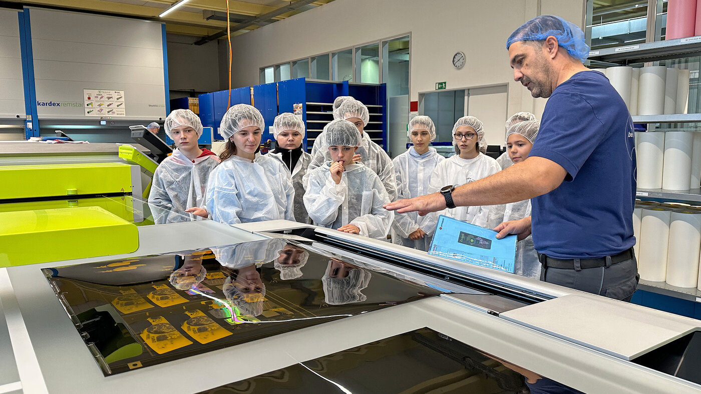 Kinder stehen vor der Maschine in der Druckformenherstellung