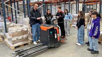 Eine Junge steht auf einem fahrbaren Palettenhubwagen.