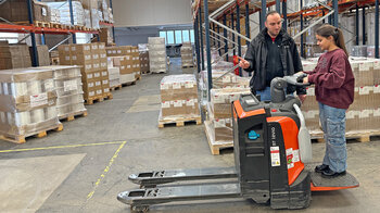 Ein Mädchen steht auf einem fahrbaren Palettenhubwagen.