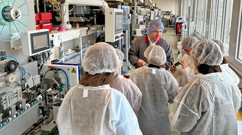 Ein Mitarbeiter mit den Kindern vor der Tubenmaschine