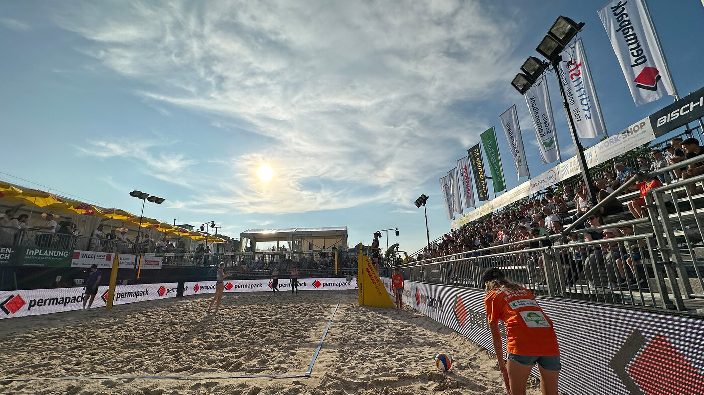 Beachvolleyball Center Court in der Abendsonne. Die Werbebande zeigt das Permapack-Logo. (