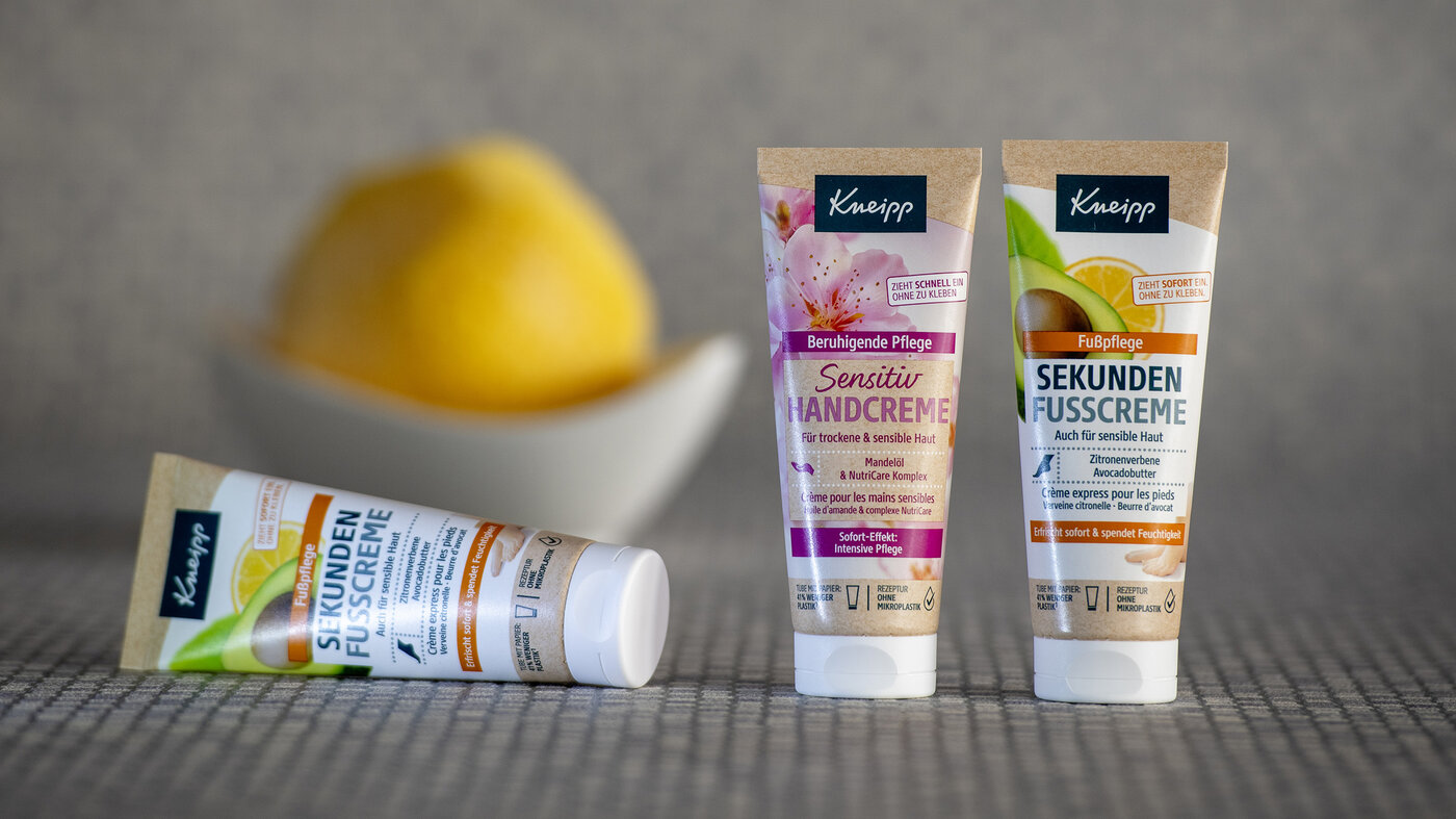 Drei Paper-Tuben mit Hand- und Fusscreme vor einem verschwommenen Hintergrund.