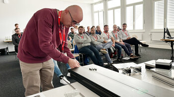 Ein Referent zeigt die Montage einer 3D-Kopplung an einem Modell.