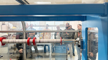 Veranstaltungsteilnehmer vor einer Rollenschneidmaschine.