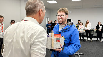 Der Gewinner der Klebe-Challenge bekommt sein Siegerpaket überreicht und freut sich.