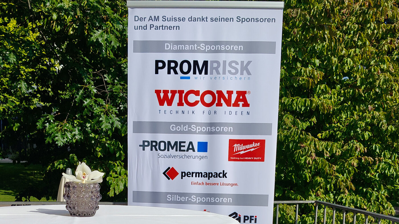 Roll-Up mit den Logos der AM-Suisse-Verbandspartner auf einer Terrasse