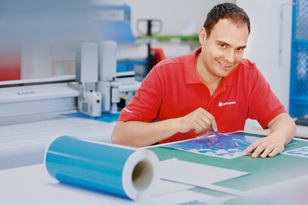 Mann mit Stanzteilen vor Plotter-Maschine